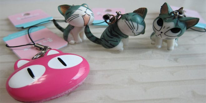A group of cat figurines and a pink key ring on a table.