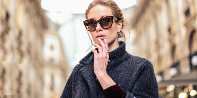 A woman wearing sunglasses and a coat.