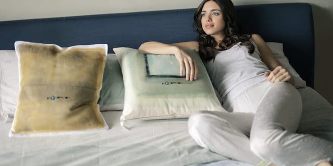 A woman laying on a bed with pillows.