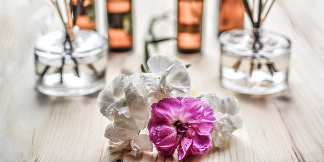 A bouquet of flowers and reed diffusers on a wooden table.