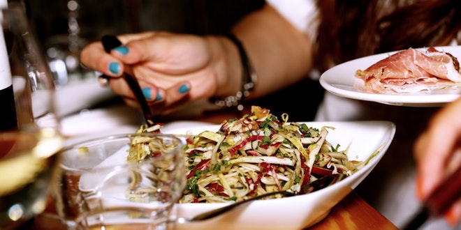 A woman is holding a plate of food and wine.