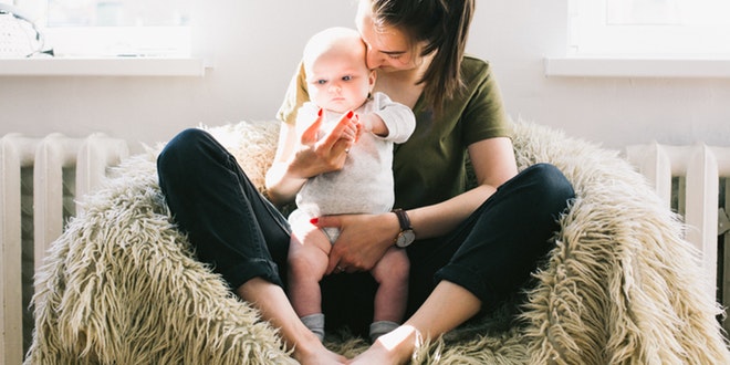 A woman is sitting in a chair holding her baby.