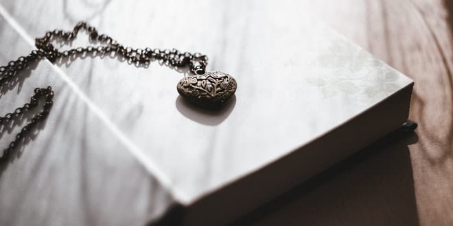 A book with a heart pendant on top of it.