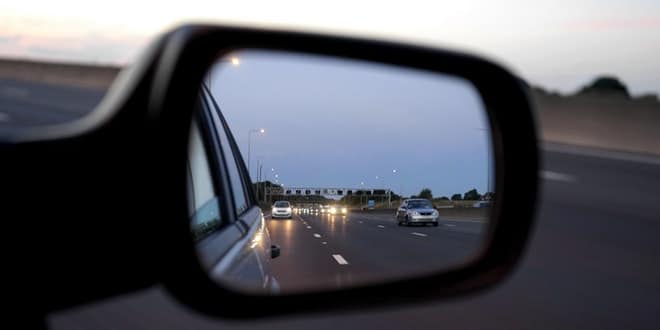 A side view mirror of a car on a highway.