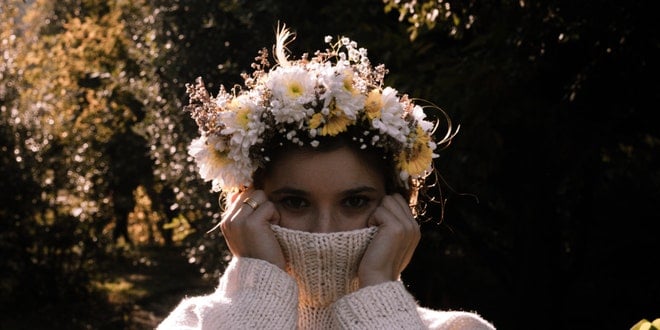 A girl in a sweater with a flower crown on her head.