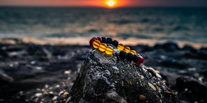A group of colorful bracelets on top of a rock at sunset.