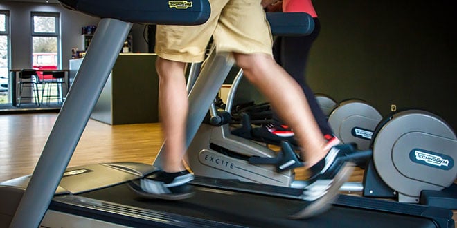 A person running on a tread machine in a gym.