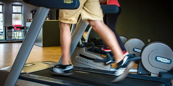 A person running on a tread machine in a gym.
