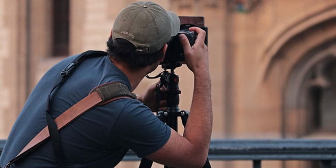 A man with a camera taking a picture of a building.