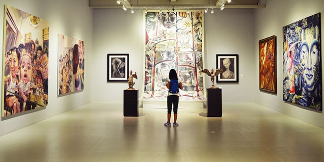 A woman looking at paintings in a museum.