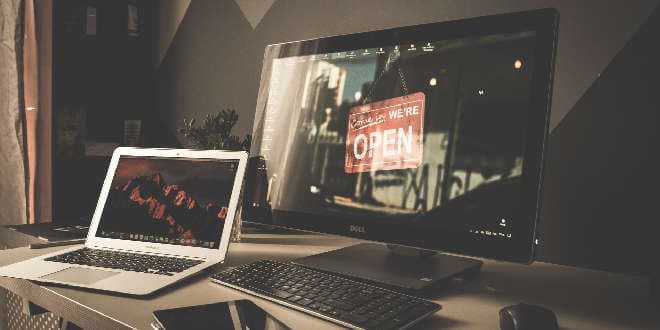 A desk with a laptop, monitor, and keyboard.