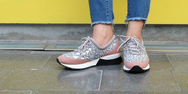 A woman wearing a pair of sneakers with sequins.