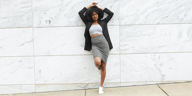 A black woman leaning against a wall.