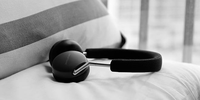 A black and white photo of a pair of headphones on a bed.