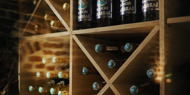 A wooden wine rack with bottles on it.