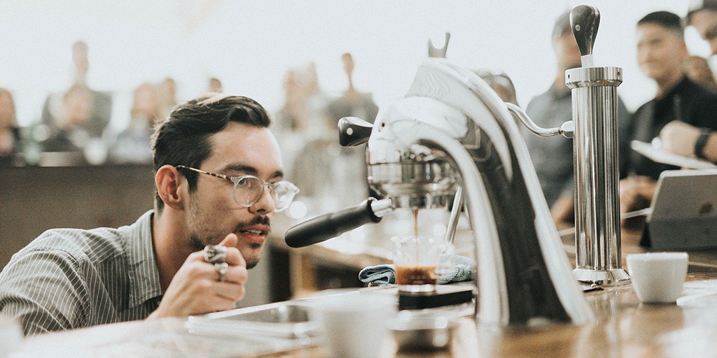 A man is making coffee in a coffee shop.