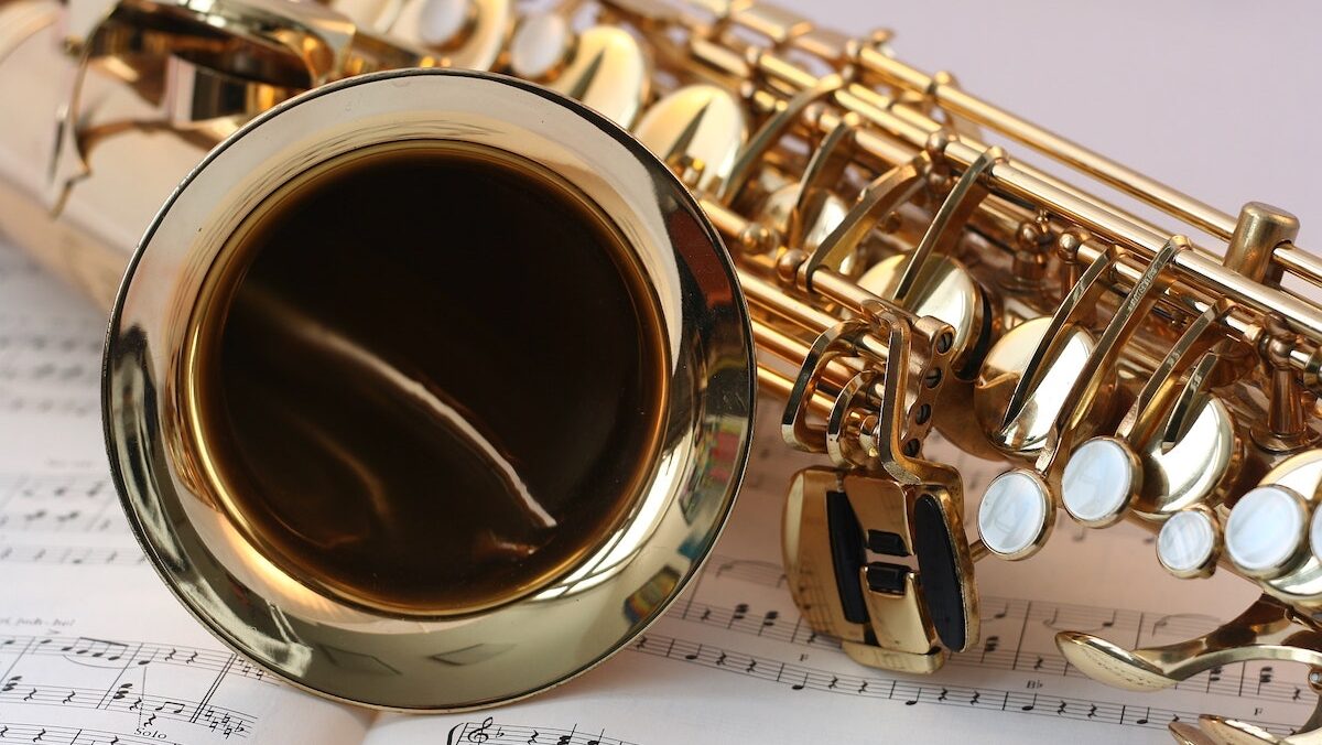 A gold saxophone sits on top of a sheet of music.