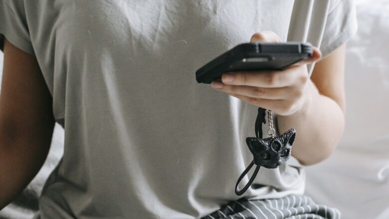 A woman sitting on bed and messaging on smartphone.