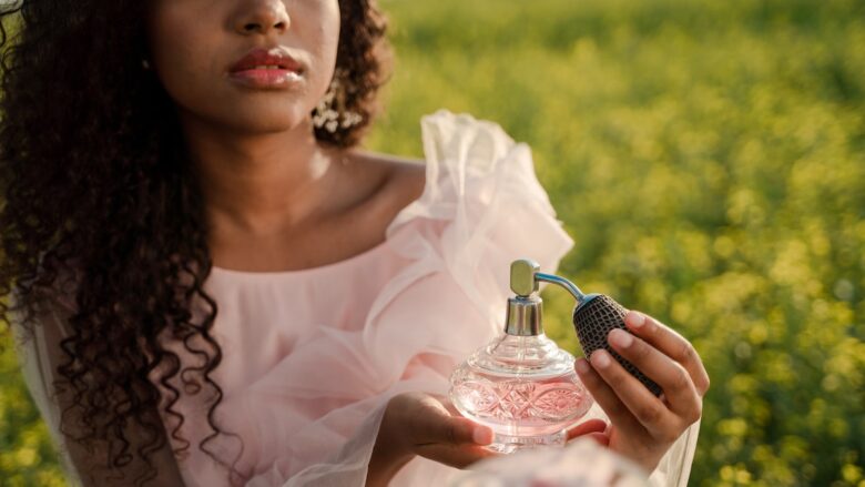 A black woman holding a perfume bottle in a field.