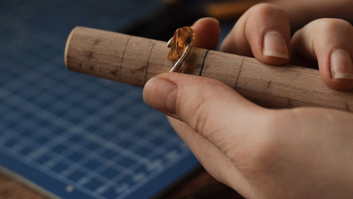 A person cutting a piece of wood into a ring.