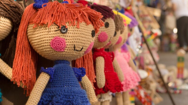 A row of brown purple red knitted crocheted dolls.