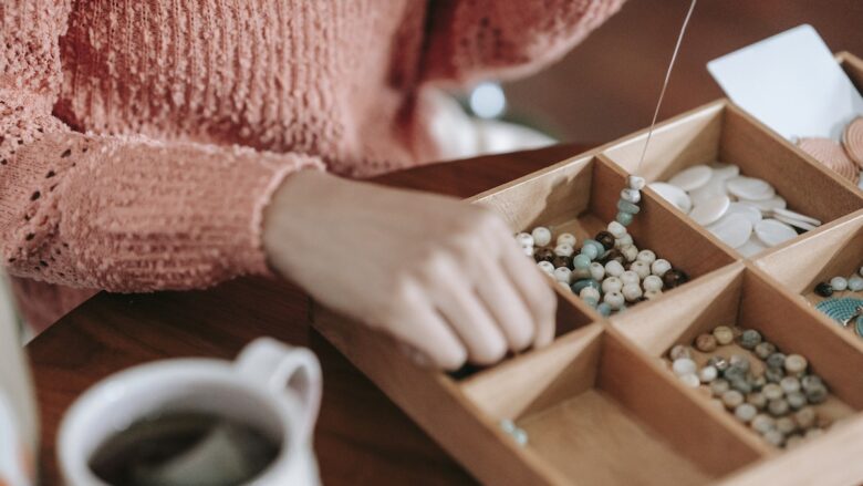 A woman is putting beads into a wooden box.
